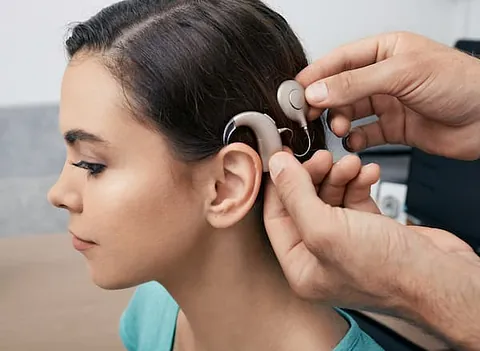 Frau-mit-braunen-Haaren-bekommt-ein-Cochlea-Implantat-am-Ohr-installiert
